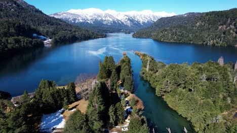 snowy mountains above blue lake water in argentina, aerial view