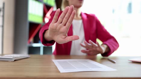woman making a stop gesture over a document on an office desk