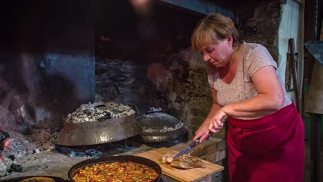 slow motion of a waitress slicing a piece of pork meat beside a wooden fired oven