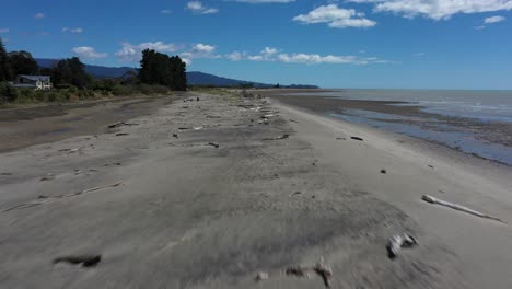 Flyover-aerial-of-sandbar-with-driftwood-on-a-sunny-day