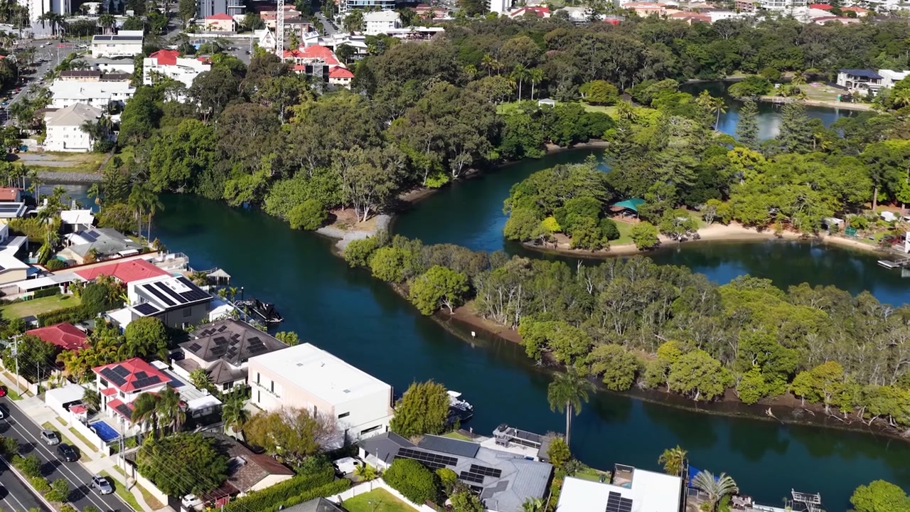 Toma aérea con dron de un río serpenteante a través de exuberantes barrios suburbanos en Queensland, Australia.
