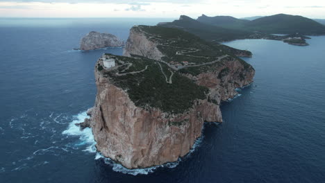 orbital aerial view of the cliff and lighthouse located on cape caccia on the island of sardinia and during sunset