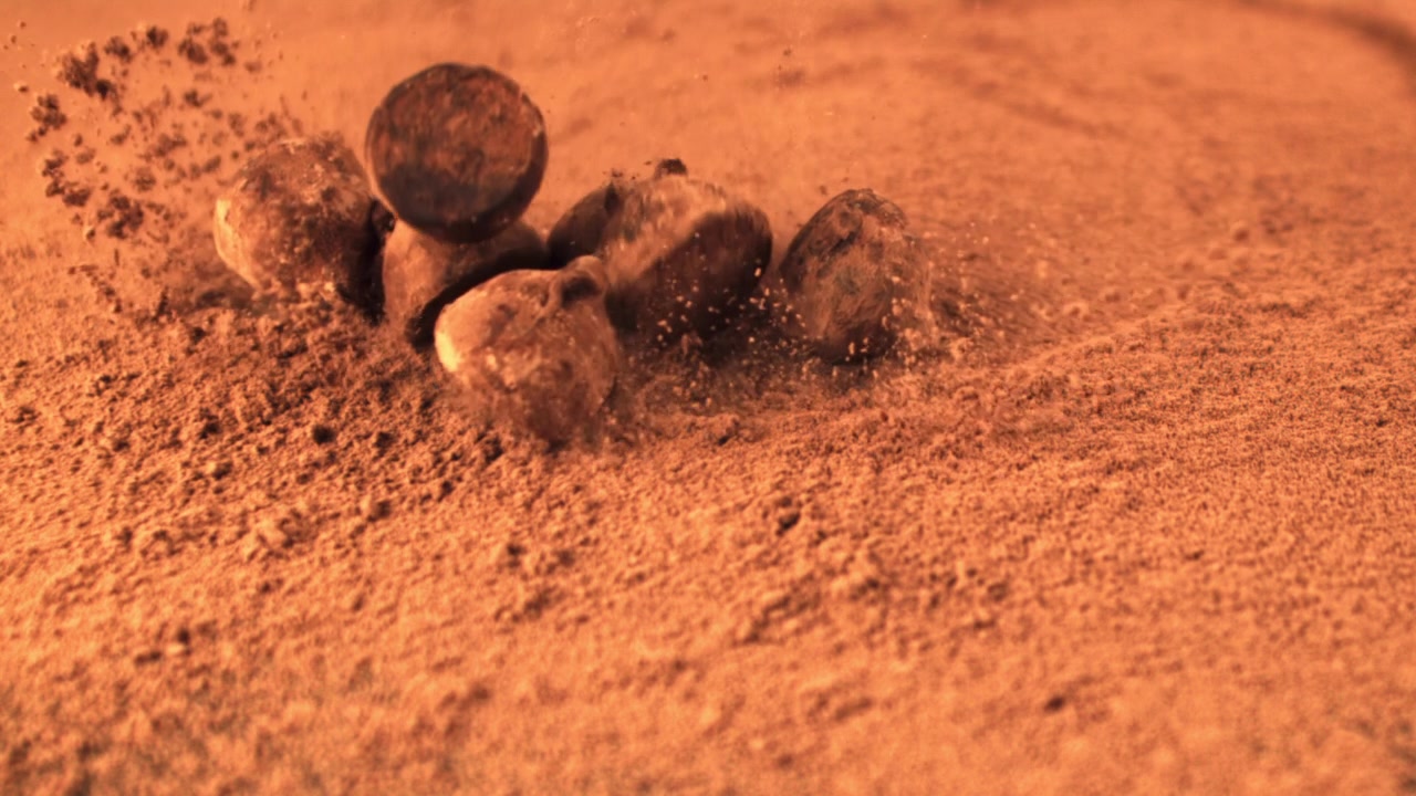 Tartufi al cioccolato che cadono sul cacao in polvere al rallentatore