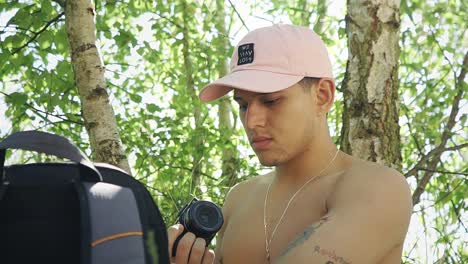 joven fotógrafo turista hispano quitando la tapa del lente para tomar fotos en un entorno natural