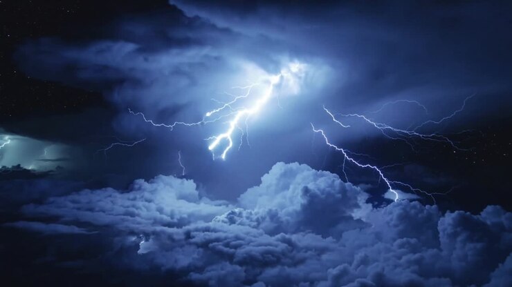 Tempesta che emette fulmini ramificati sopra le nuvole di notte, con la carica che si accumula e si rilascia per le condizioni atmosferiche.