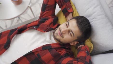 young man lying alone on the sofa in his modern home and daydreaming about the future.