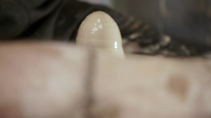 A potter teaches a woman to make clay dishes. A man takes a woman's hands