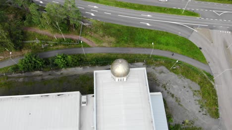 cúpula dorada y cruz adornada en la parte superior del techo de la iglesia en un lote abandonado por la calle de asfalto y árboles verdes en el día soleado, antena aérea