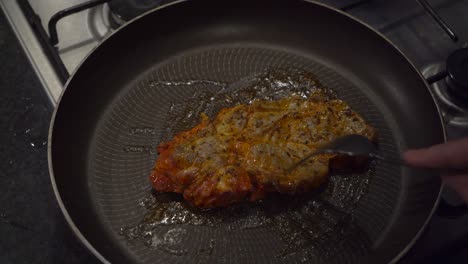 vista de ángulo alto: el bistec de ternera se voltea en una sartén caliente en la estufa