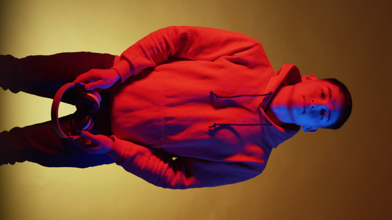 Man Wearing Headphones and Hoodie in Colorful Lighting