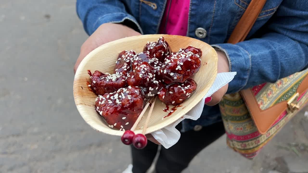 fotografía cinematográfica de una mujer sosteniendo un plato de pollo crujiente picante de corea del sur durante el día en calcuta, india