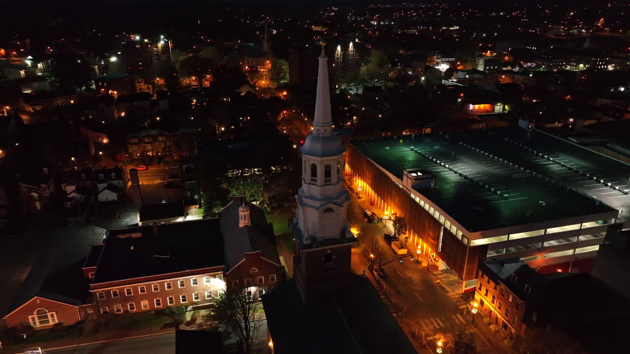 Aerial orbit of steeple in dark of night. Aerial city establishing shot in USA.