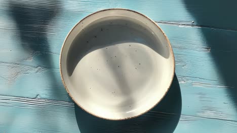un plato de cerámica blanco vacío en una mesa azul