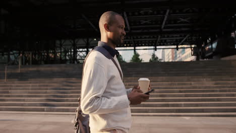 african american businessman walking through city using smart phone