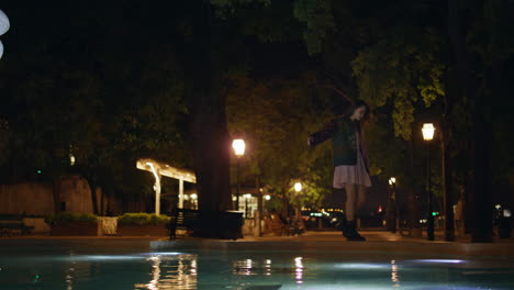 girl walking fountain edge calm night. woman relaxing at evening town square.