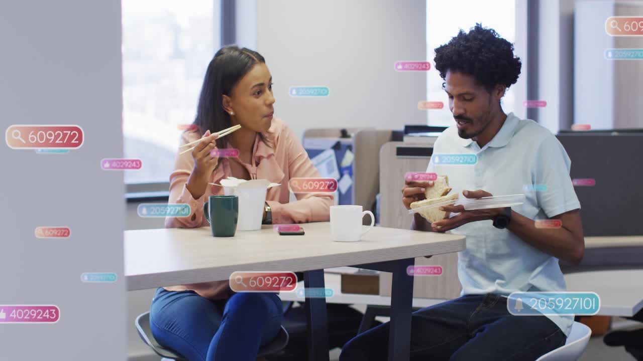 Woman lifting chopsticks man opening boxed meal, causing data tags floating over office lunch chat