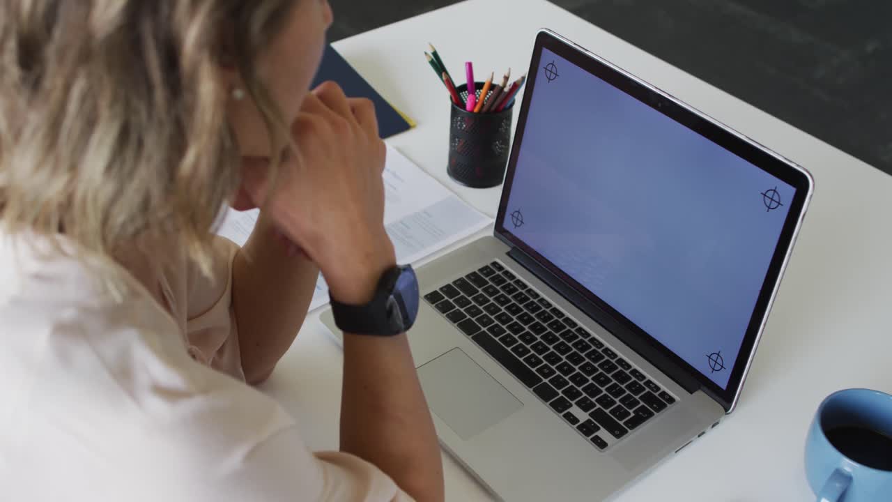 mujer de negocios caucásica sentada en un escritorio y usando una computadora portátil con espacio de copia en la pantalla