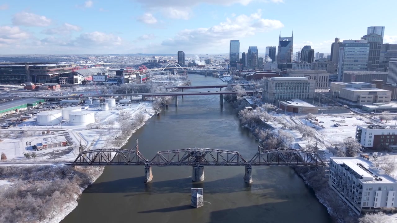 Kış kar yağışı sonrası Nashville şehir merkezinin havadan drone görüntüsü, Tennessee. Cumberland Nehri, şehir silüeti, köprüler ve karla kaplı manzara, büyüleyici bir kentsel kış panoraması oluşturuyor.