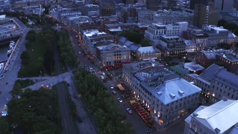 aerial shot over montreal's old port at dusk, with the city lights reflecting on the water and the ferris wheel glowing. captures the serene beauty and vibrant atmosphere of the evening.