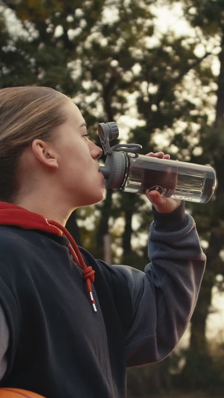 Young woman drinking water on a basketball court