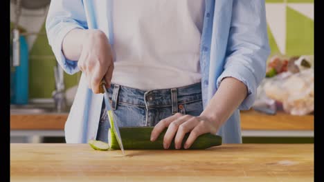 woman chopping cucumber in kitchen