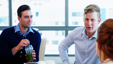 ejecutivos discutiendo mientras desayunan juntos en la cafetería
