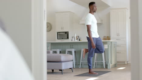 Focused-african-american-man-stretching-in-sunny-living-room,-slow-motion