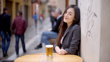 Friendly-young-woman-sitting-enjoying-a-beer