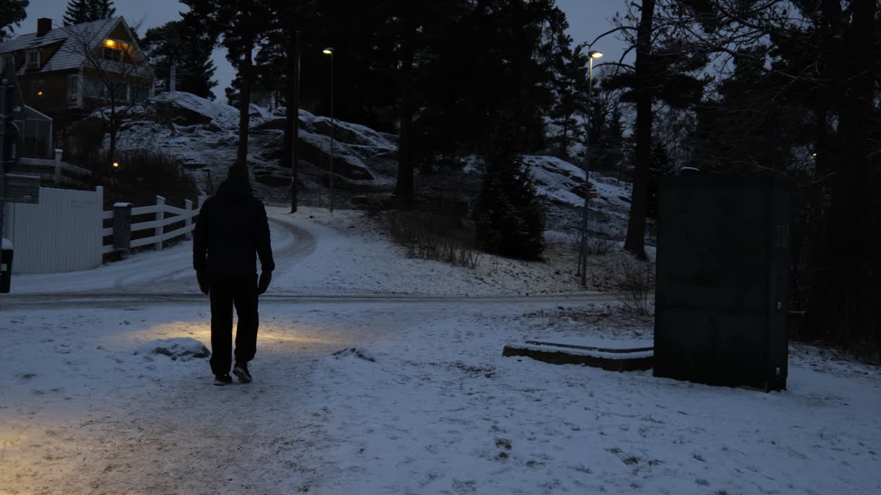 눈 덮인 마을에서 밤에 걷는 남자