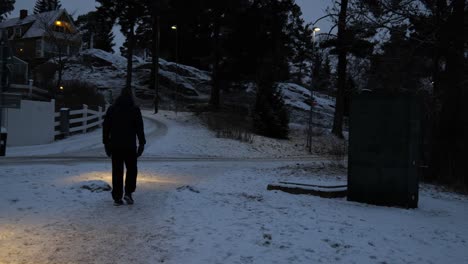 man walking at night in a snowy village