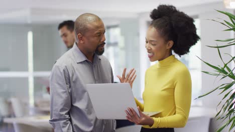 Group-of-diverse-business-people-using-laptop-and-talking-in-office,-slow-motion