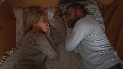 lovely couple lying in bed looking each other, having a romantic conversation face to face on a winter day