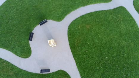 Aerial-rising-view-above-round-landscaped-cemetery-garden-footpath-seating