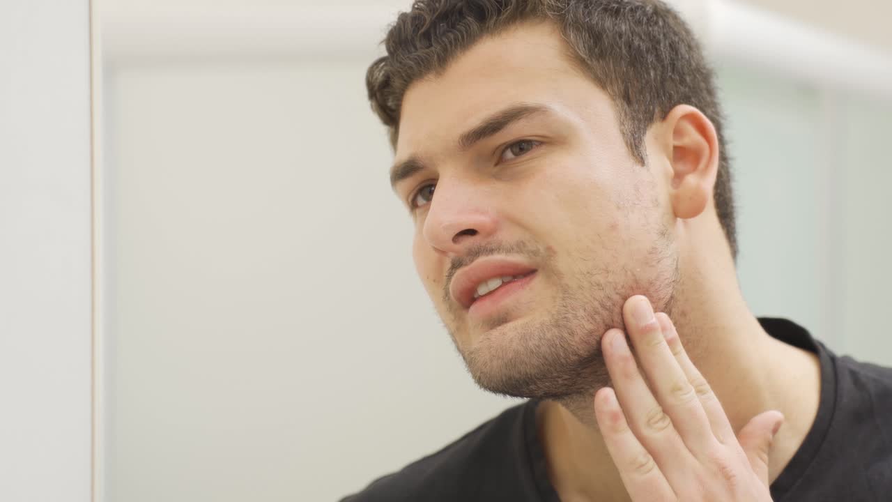 그 남자는 거울에 자신의 얼굴을 쳐다본다.