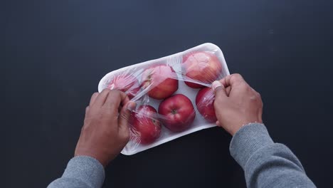 manos desempaquetando un paquete de manzanas rojas