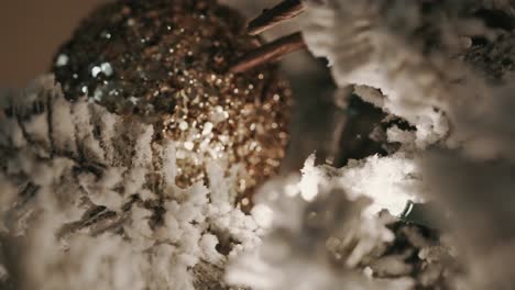 focus-rack-to-a-close-up-macro-shot-of-a-gold-ornament-on-a-snow-frosted-Christmas-tree