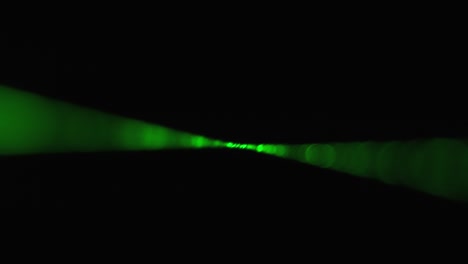 rayo láser verde sobre un fondo negro. rayo láser de potencia que brilla en la niebla