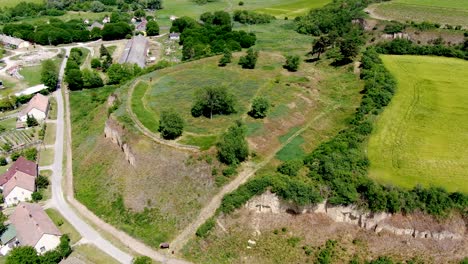 Earth-castle-in-Ersekhalma,-Hungary-featuring-green-fields-and-rugged-terrain,-aerial-view