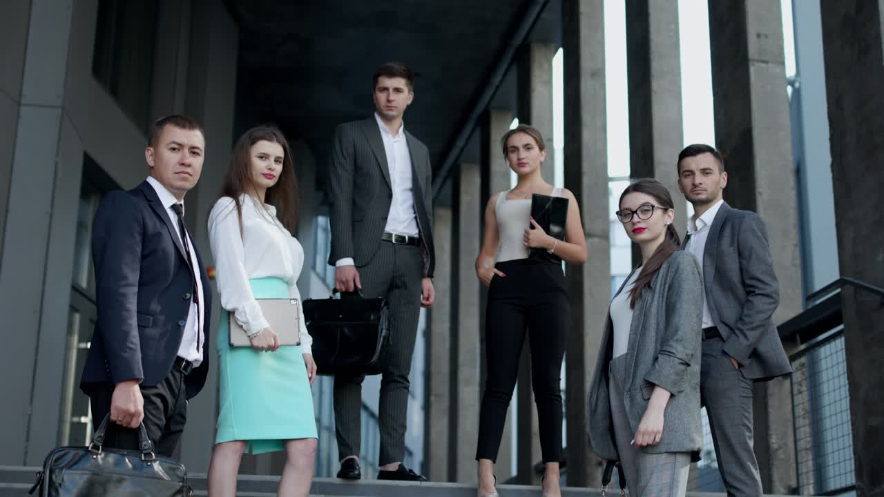 портрет успешного творческого бизнесмена и бизнесменки в формальных костюмах, смотрящих в камеру и улыбающихся на современном офисном рабочем месте.