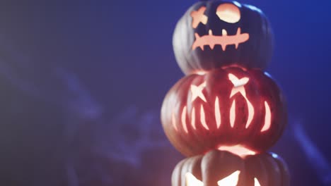 video of halloween carved pumpkins and smoke with copy space on blue background