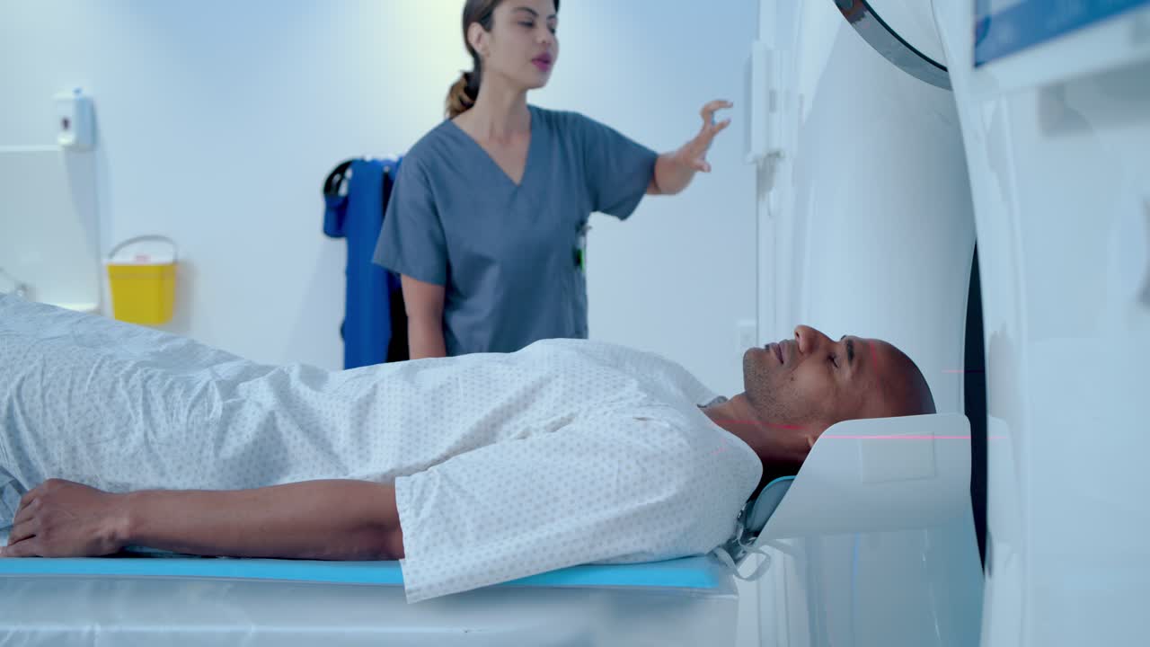 Tecnica in divisa medica che preme il pannello dello scanner in ospedale, avviando la scansione mentre il paziente è immobile