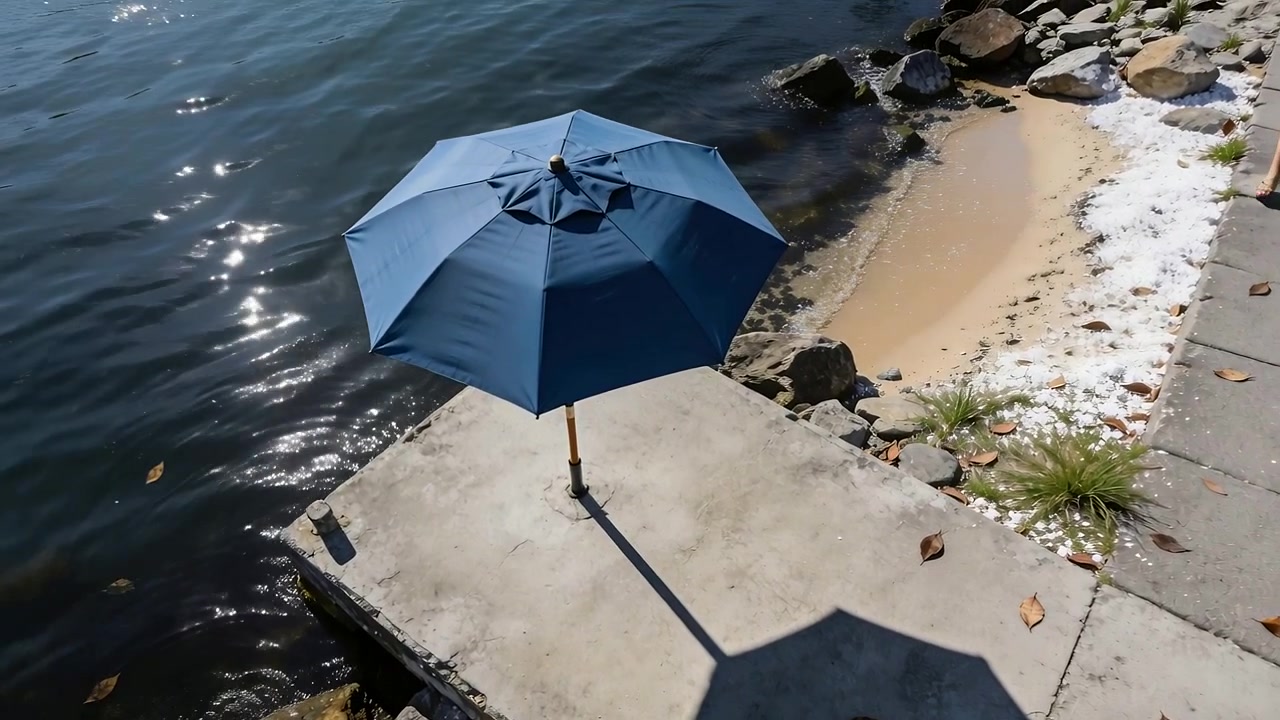 Drone in movimento che inquadra un ombrellone blu su un molo in riva al lago, con una tazza e increspature.