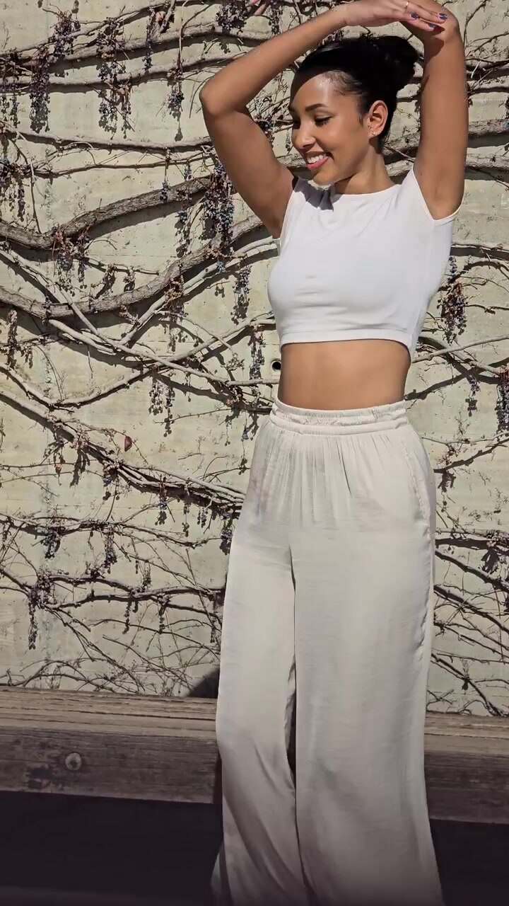 Movimento gioioso: una donna che balla elegantemente in abbigliamento casual contro una parete splendidamente strutturata