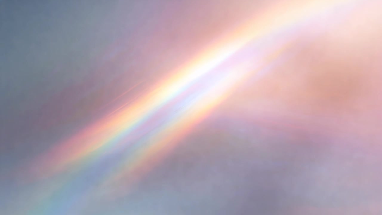 Banda di luce iridescente diagonale che si sposta e si allarga nel cielo diurno mentre la luce del sole colpisce sottili strati di nuvole.