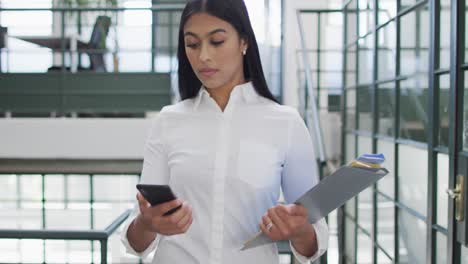 happy biracial businesswoman using smartphone at office