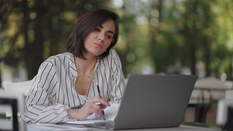 mujer pensativa morena grupo étnico hispano se sienta en una mesa en una cafetería de verano con una computadora portátil. mujer de negocios seria reflexionando sobre la resolución de problemas y la estrategia de desarrollo empresarial