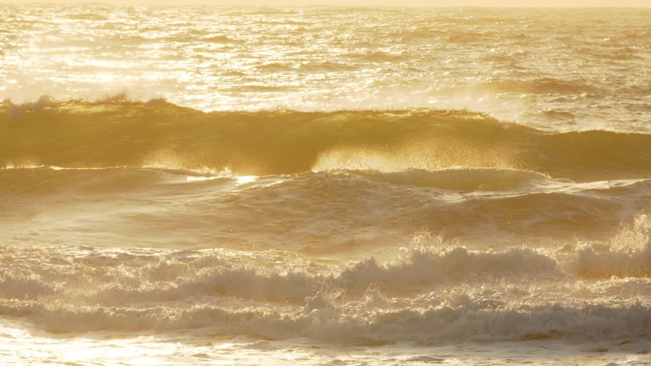 황금빛의 해가 뜨는 물결이 바다의 스프레이를 비추고