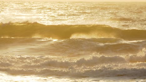 las olas chocan con el amanecer dorado iluminando el océano