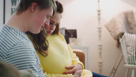 young downs syndrome couple sitting on sofa using laptop at home