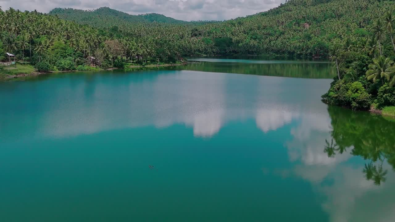 필리핀 서리가오 델 노르테 의 마후크담 호수 의 공중 무인 항공기 사진 으로 주변 의 울창 한 정글 의 아름다운 반사물 을 보여준다